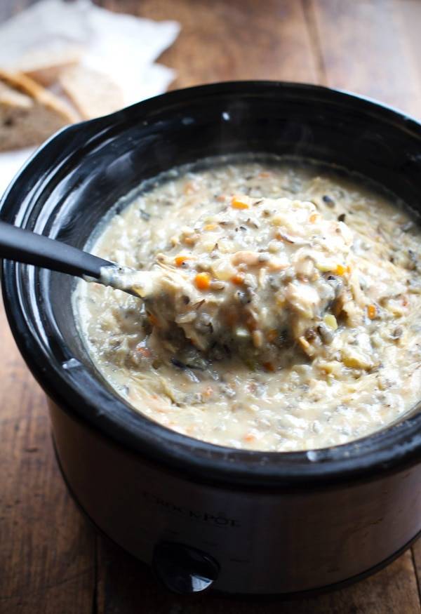 Ladle scooping up chicken wild rice soup from a crockpot. 