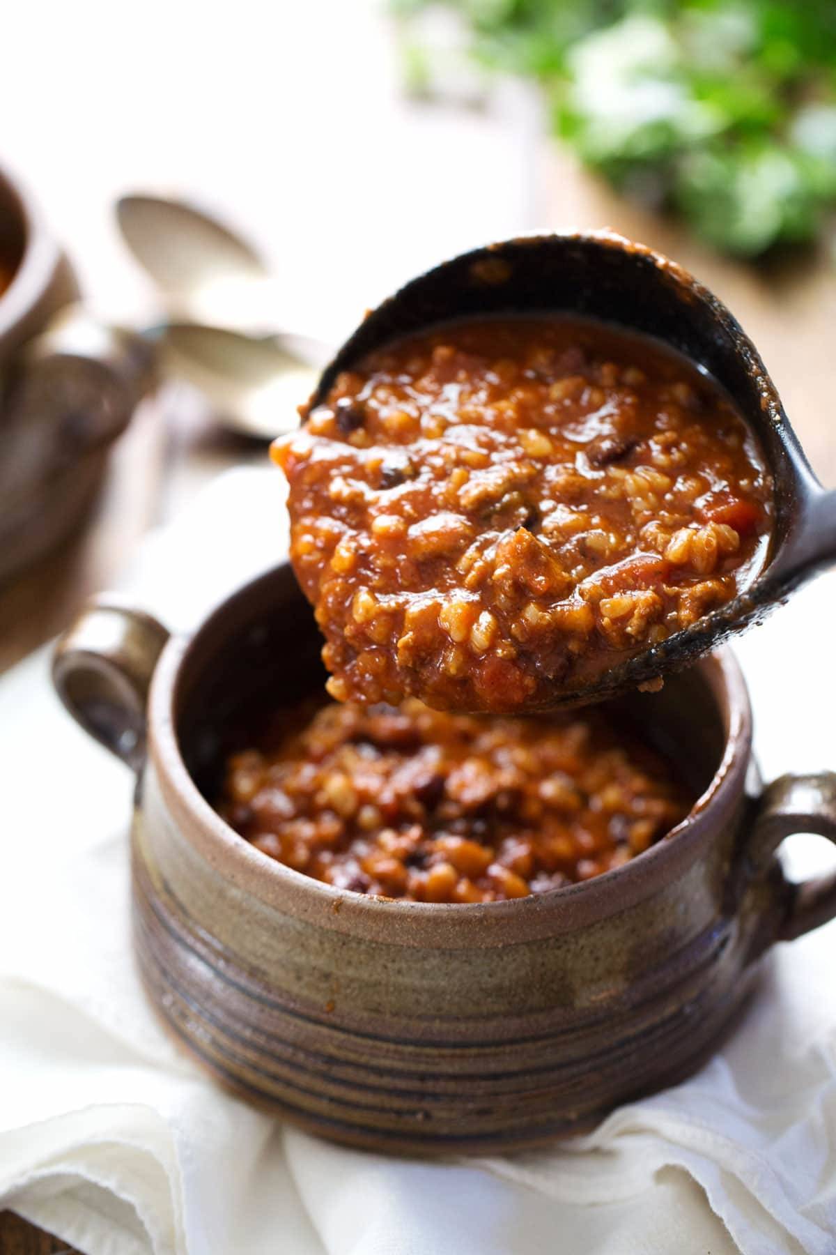 Chili in a serving spoon and in a bowl.