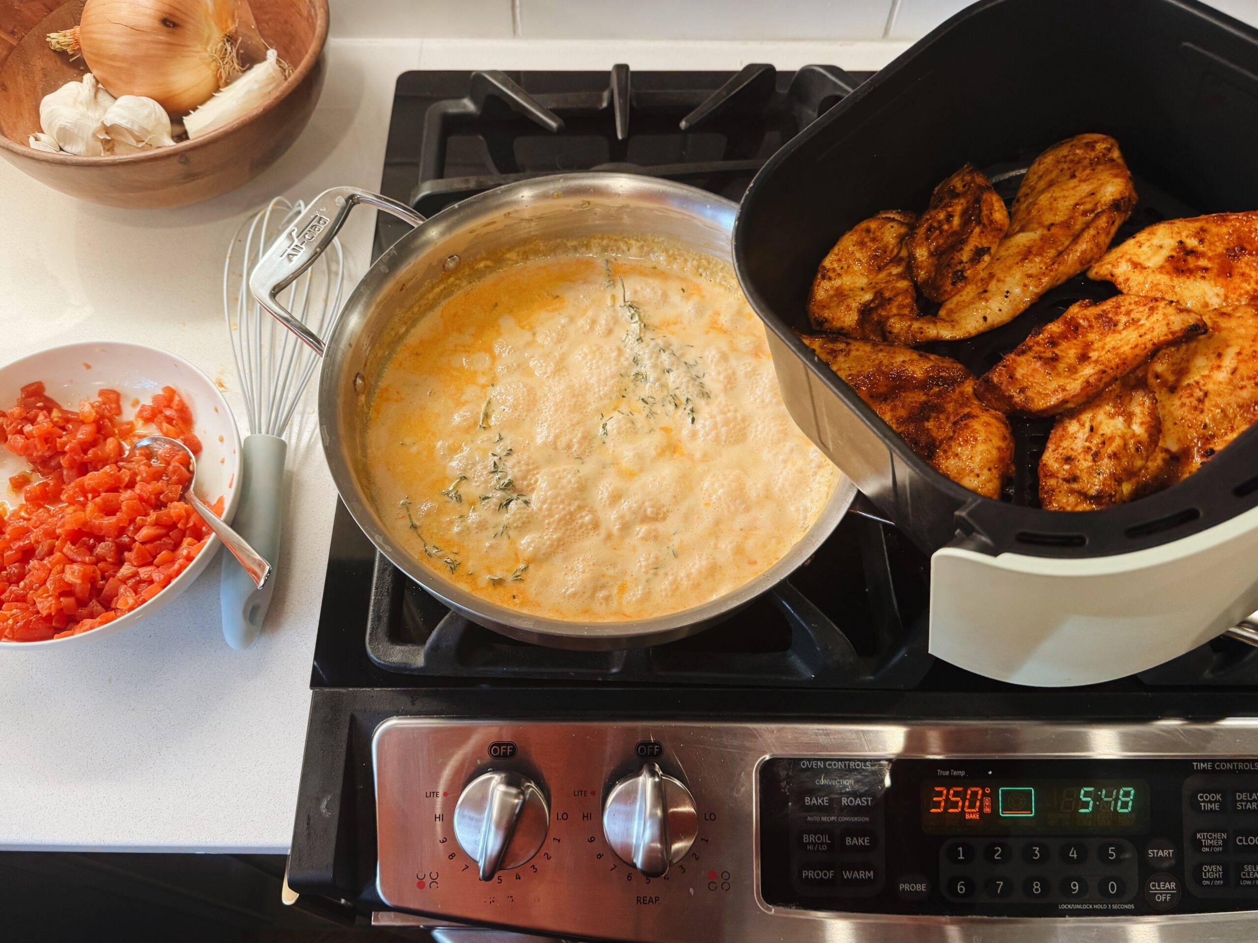 Adding air-fried chicken to a pan with sauce.