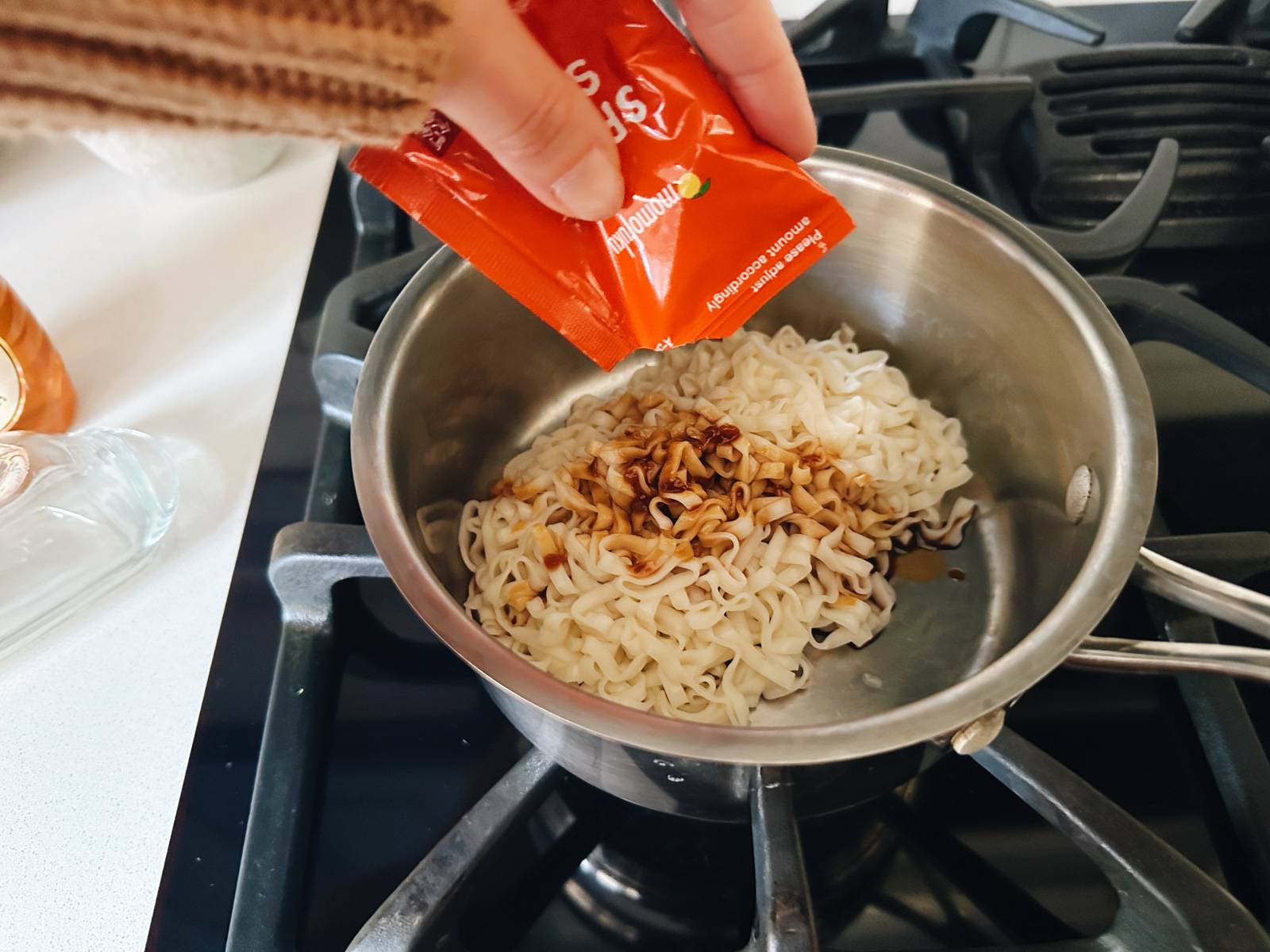 Adding sauce to a pot on the stove.