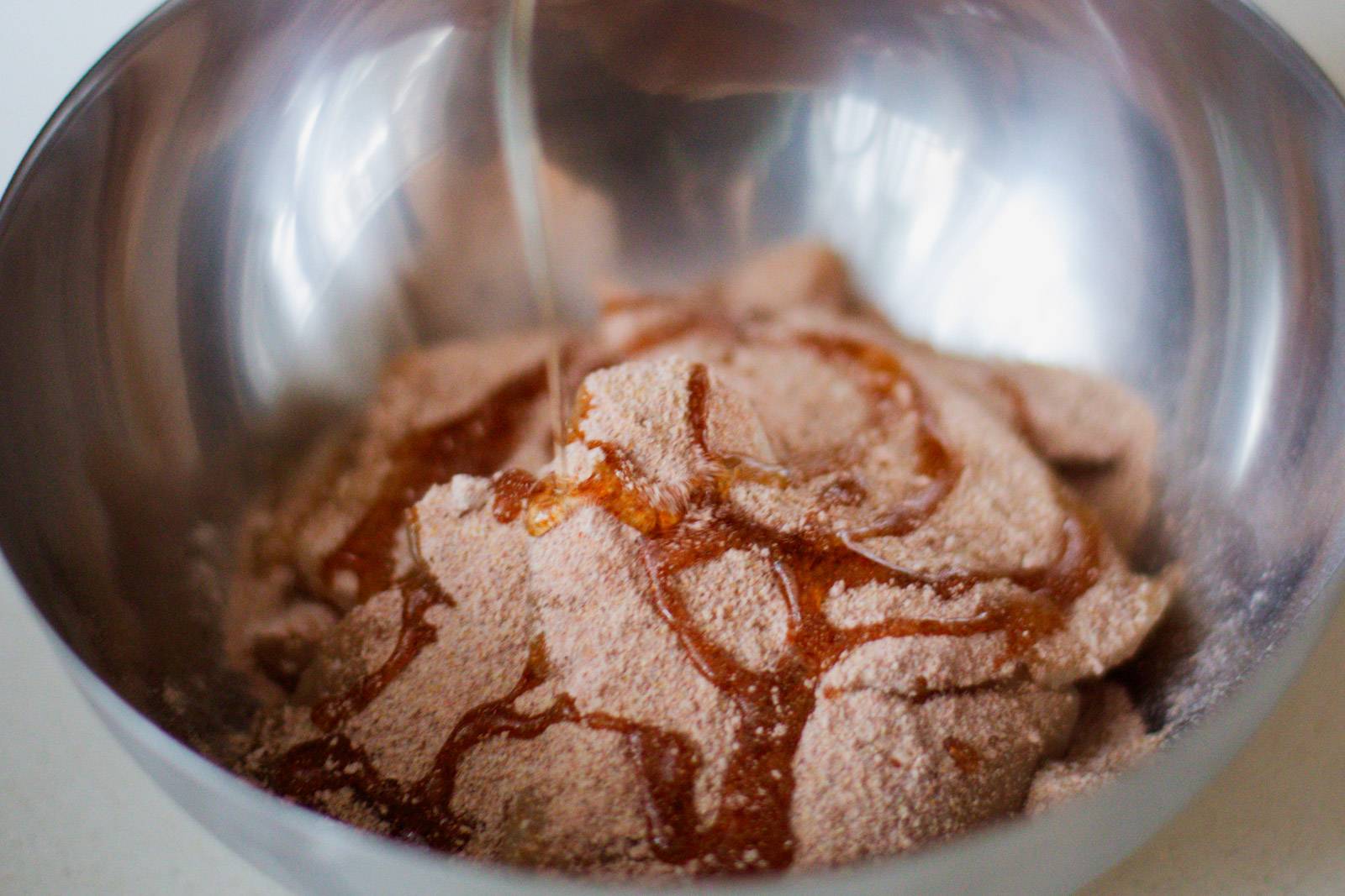 Coating chicken in spices in a bowl.