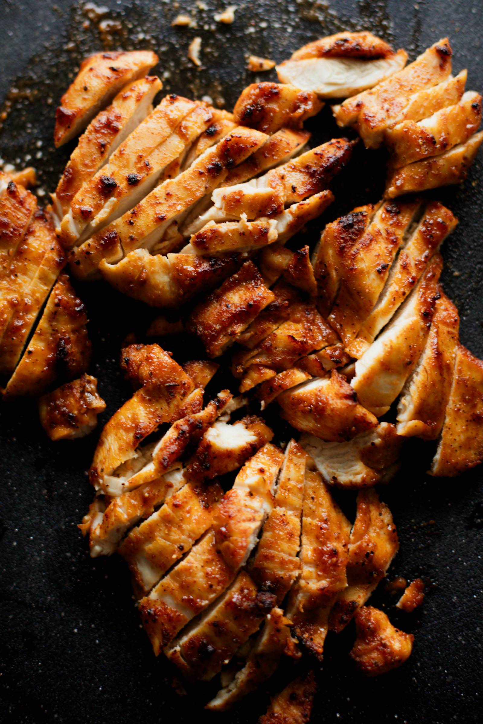 Thinly sliced air-fried chicken on a cutting board.