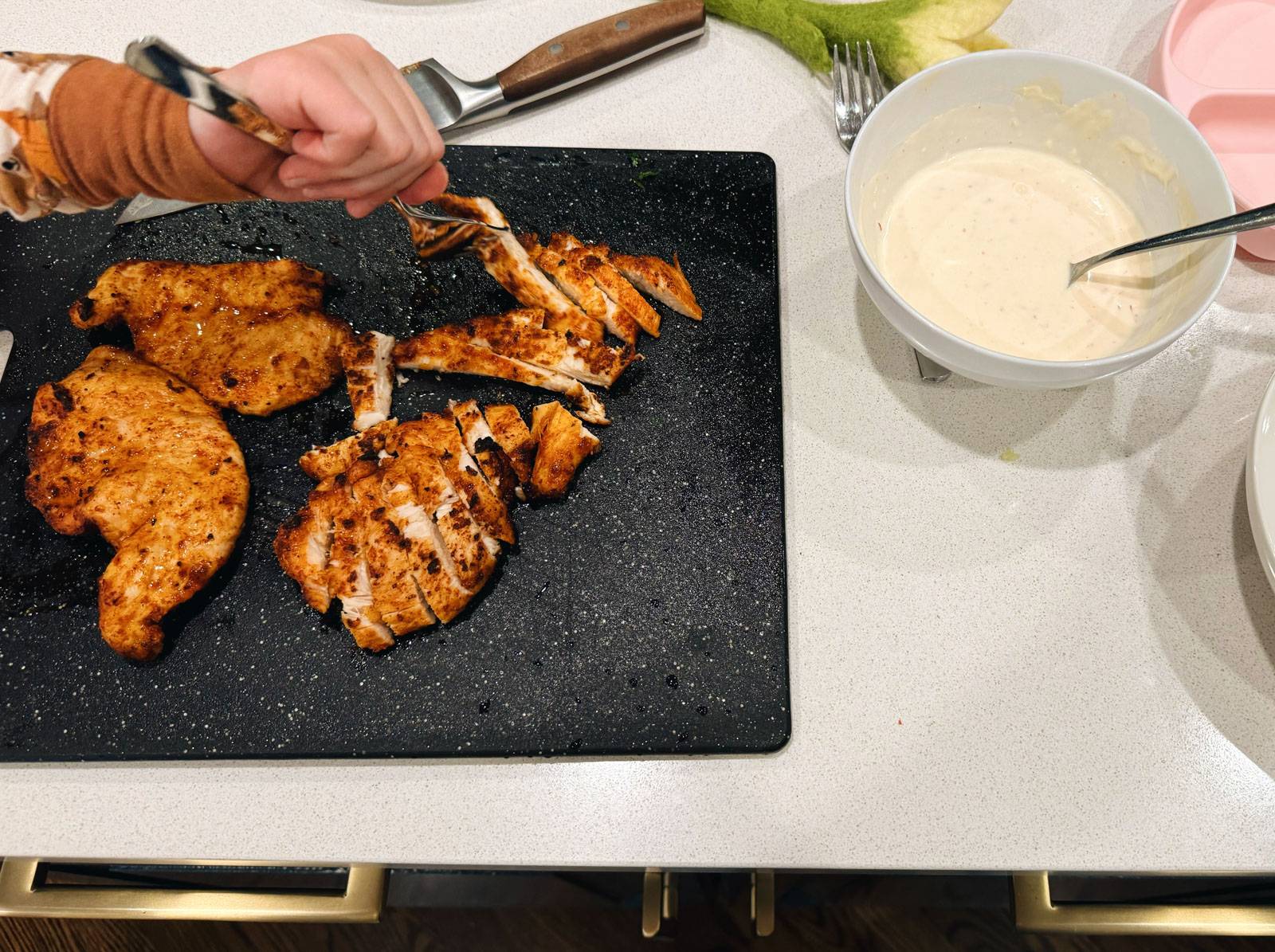 Slicing air fryer chicken on a cutting board.