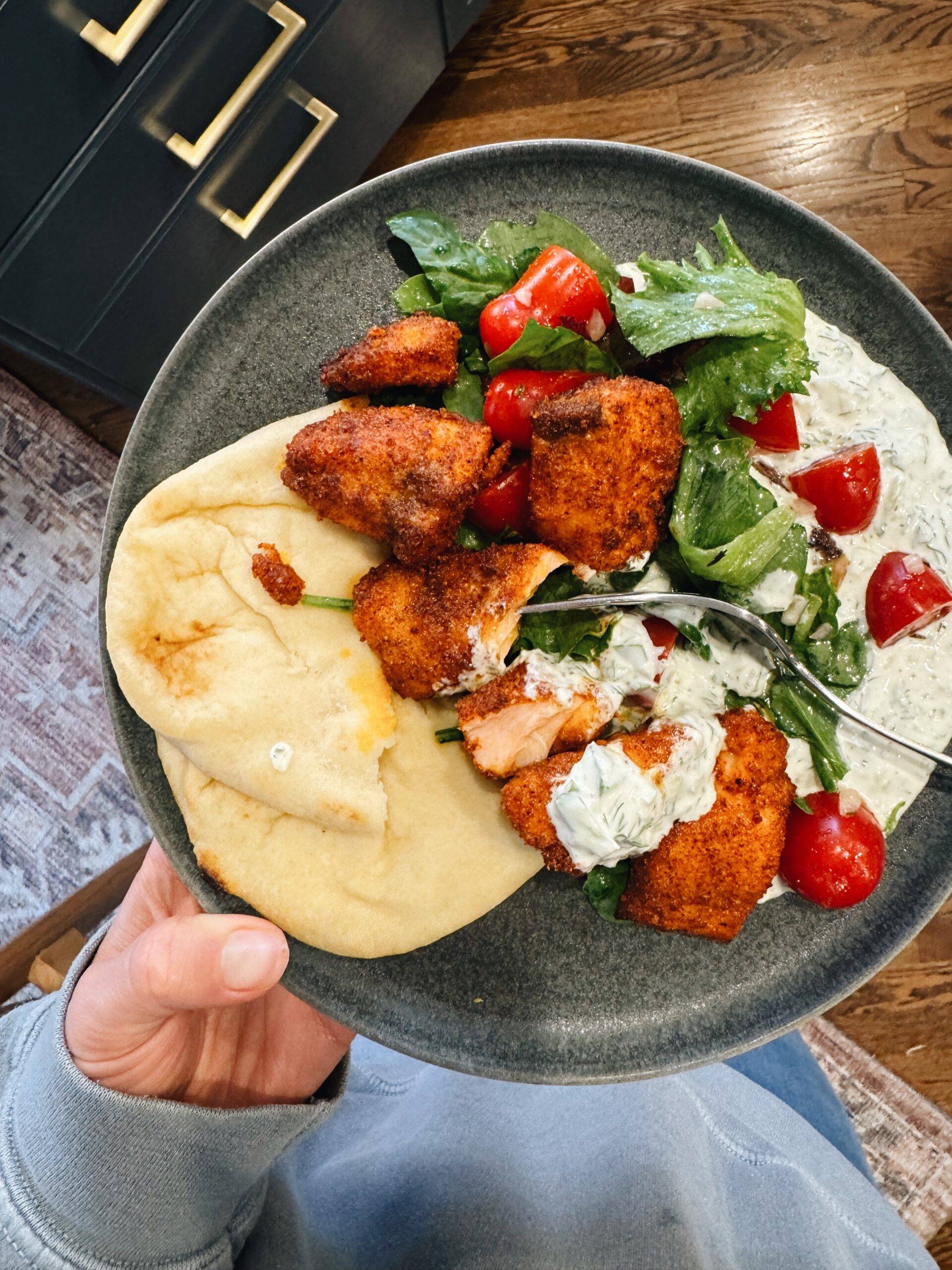 Air fryer salmon on a plate with naan, tzatziki, and salad.