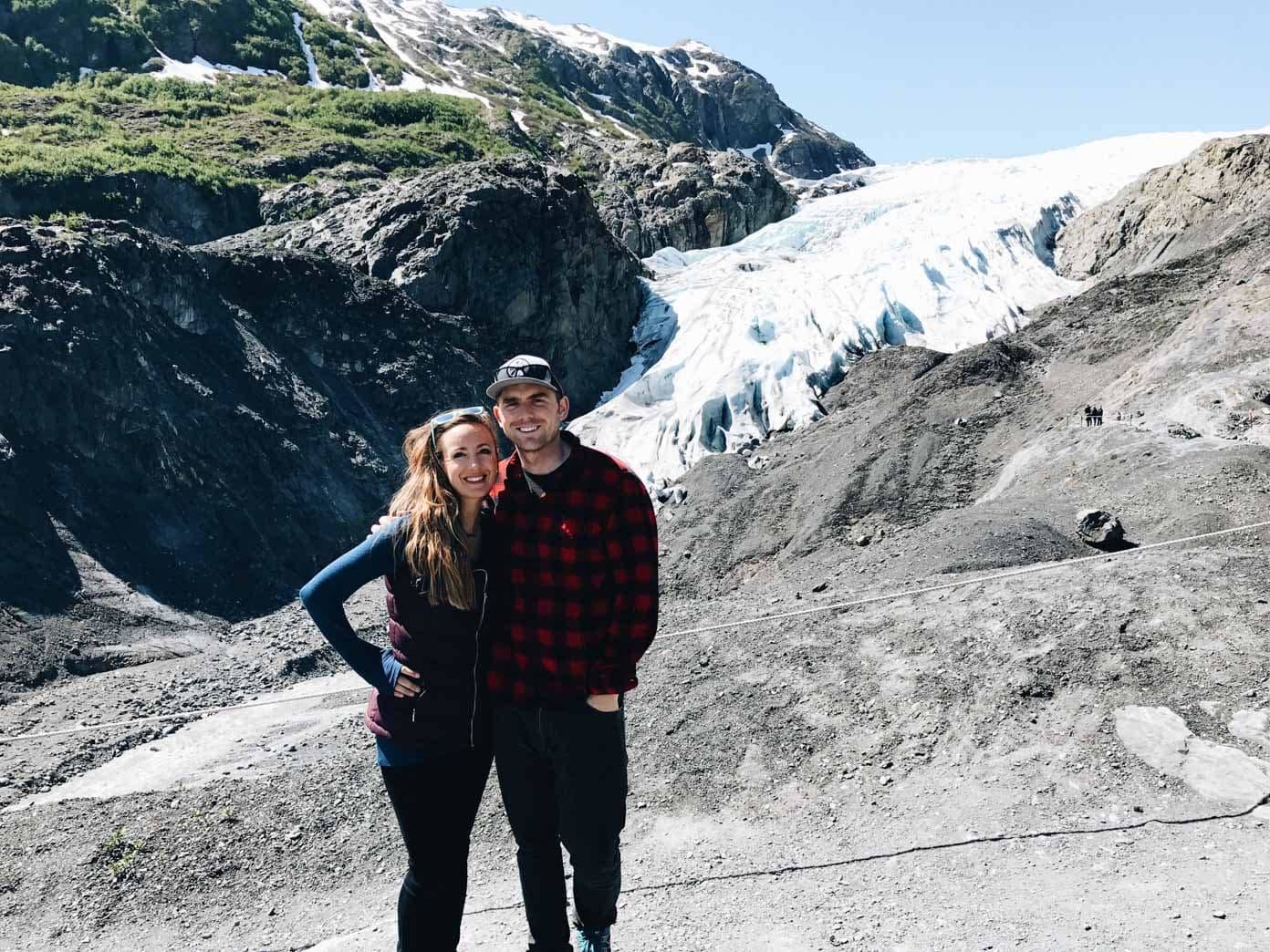 Man and woman smiling on a rocky cliff.