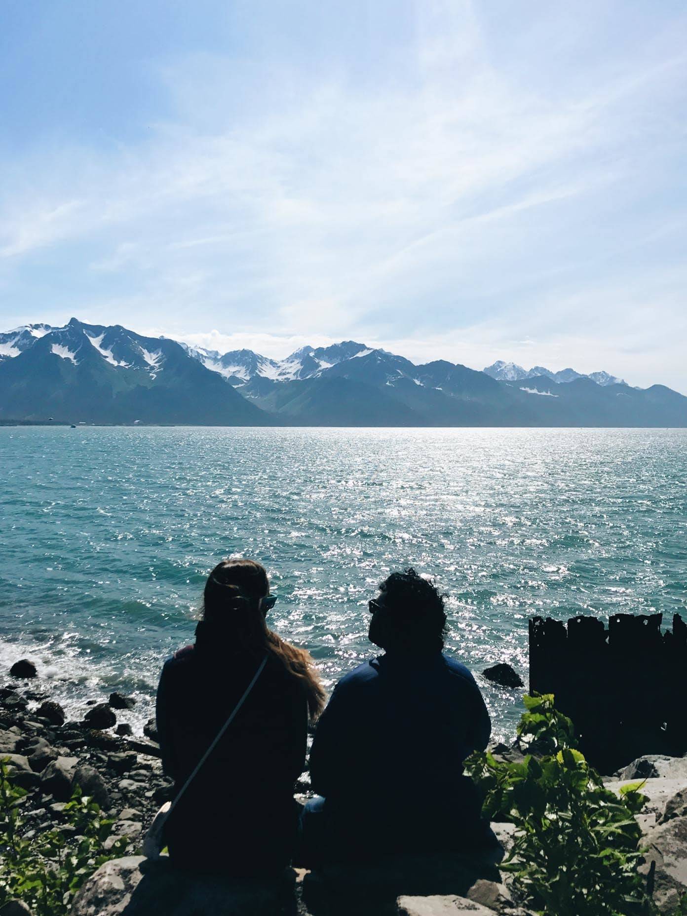 Two people sitting on rocks looking out at the water.