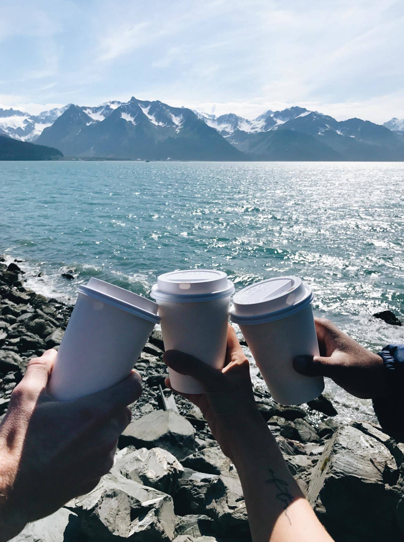 Three cups and a view of the ocean with mountains.