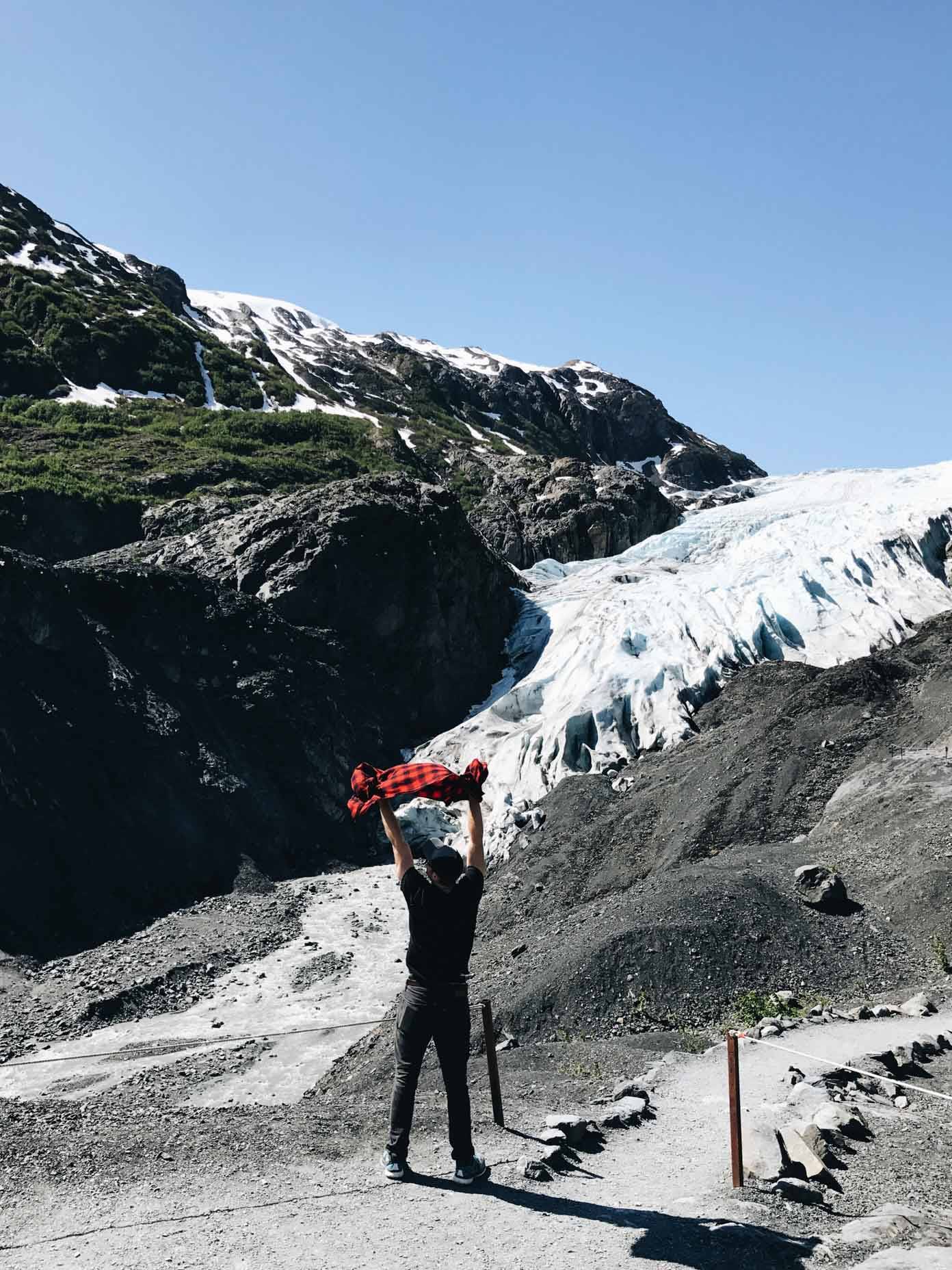 Man standing on a rocky sidewalk in the mountains.