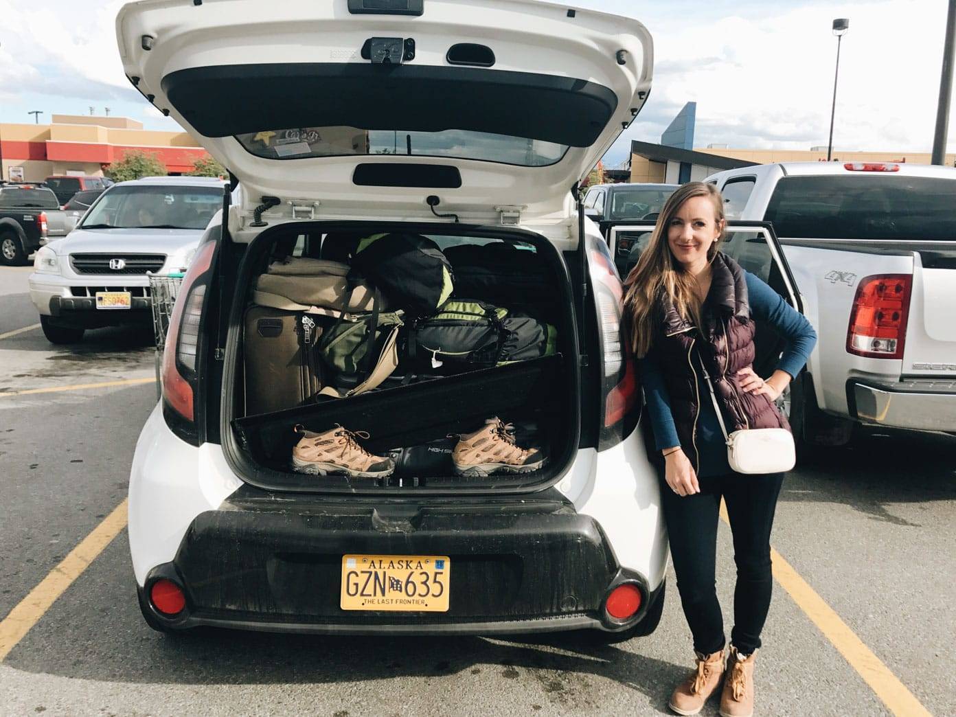 Woman standing next to a white vehicle.