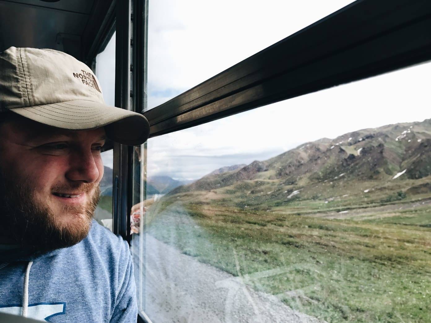 Man wearing a hat looking out a bus window.