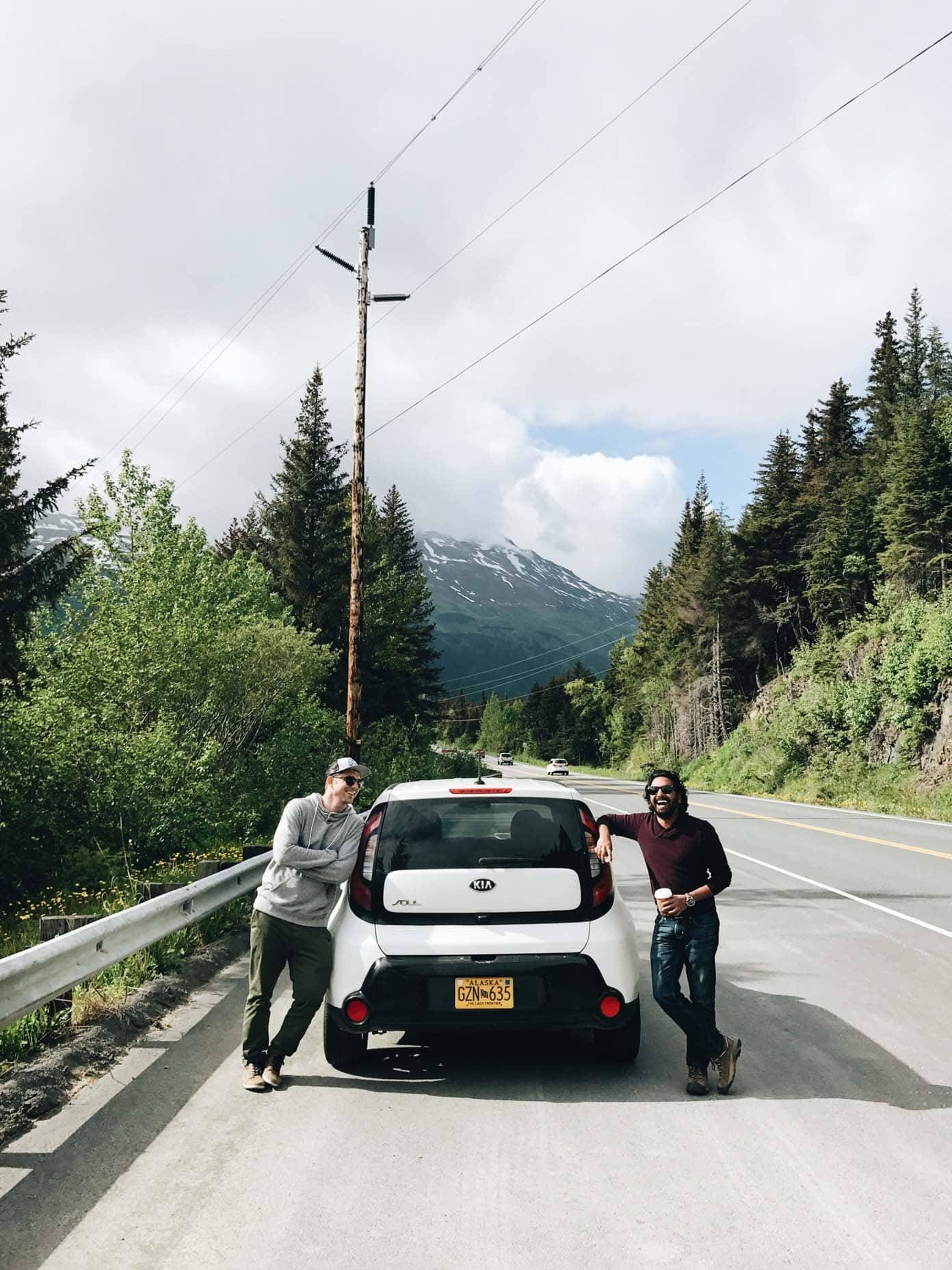 Two men standing next to a white vehicle.