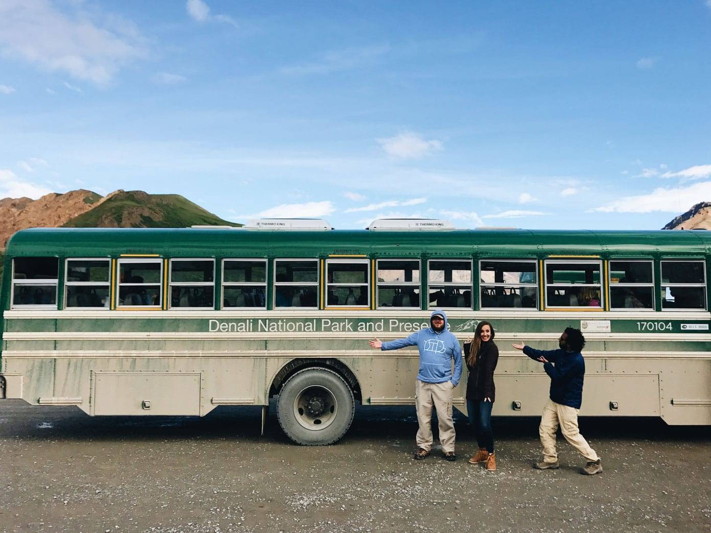 Three people in front of a bus.