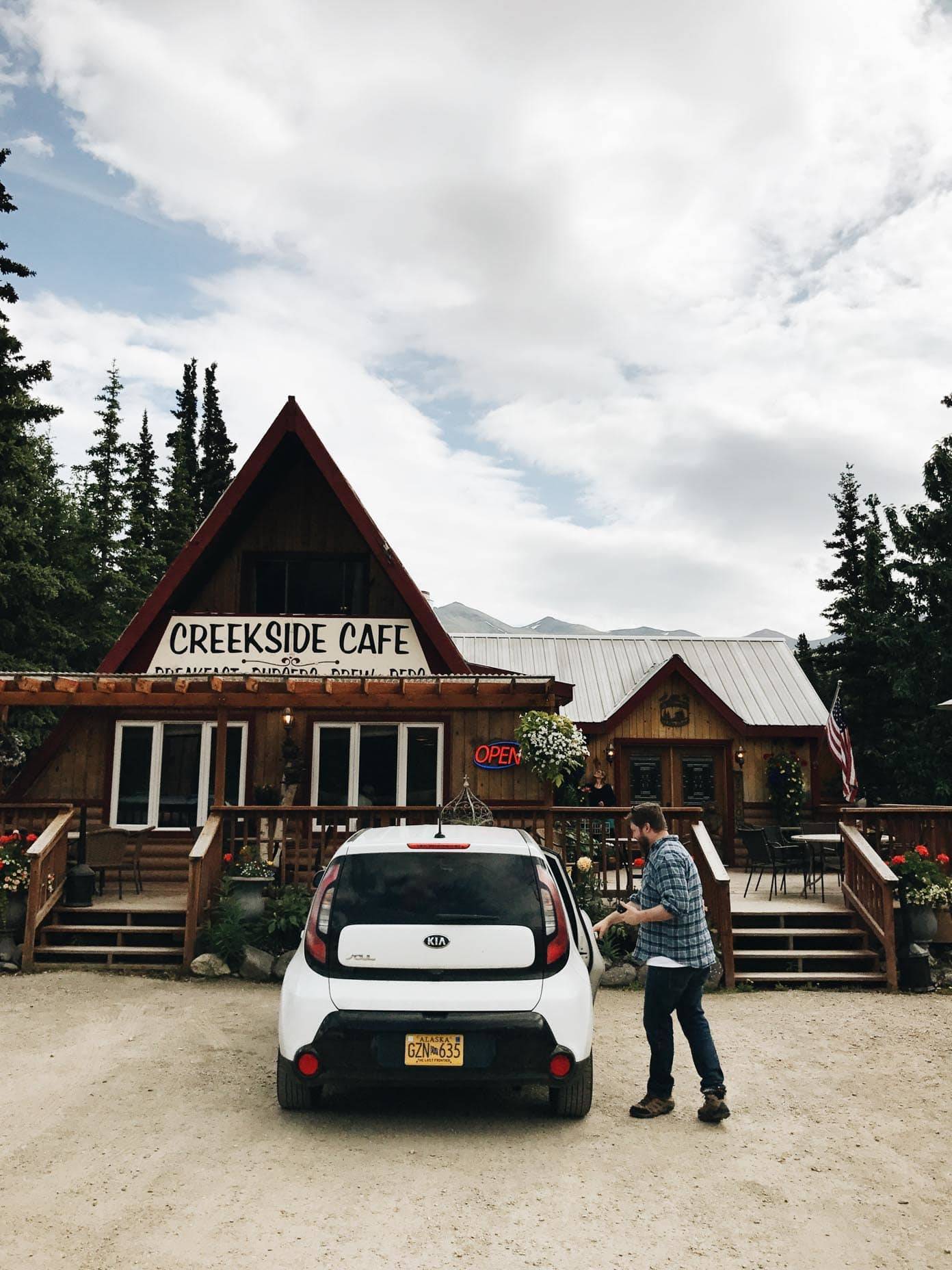 White car in front of a small cafe.