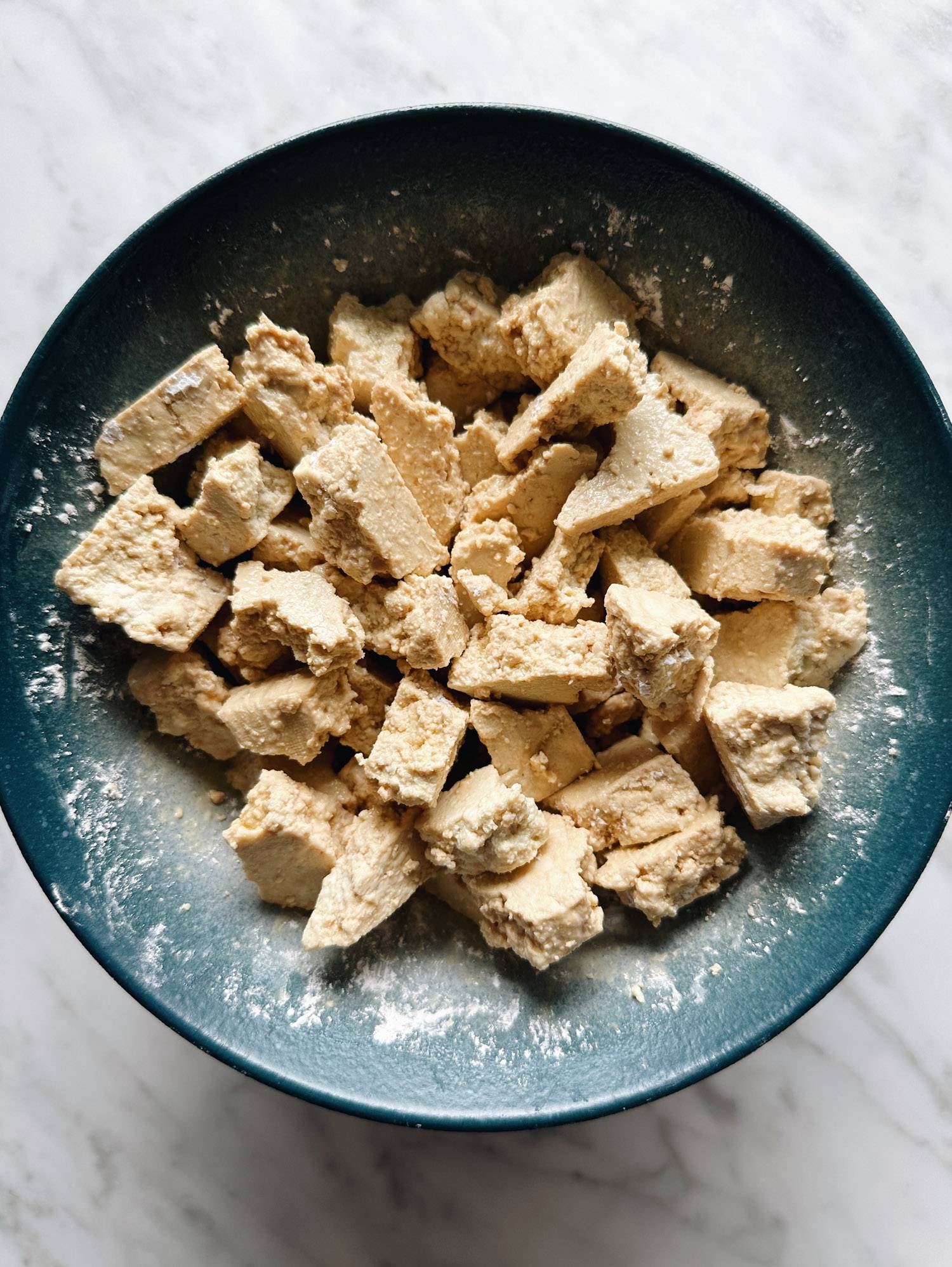 Torn tofu in a bowl covered in cornstarch.