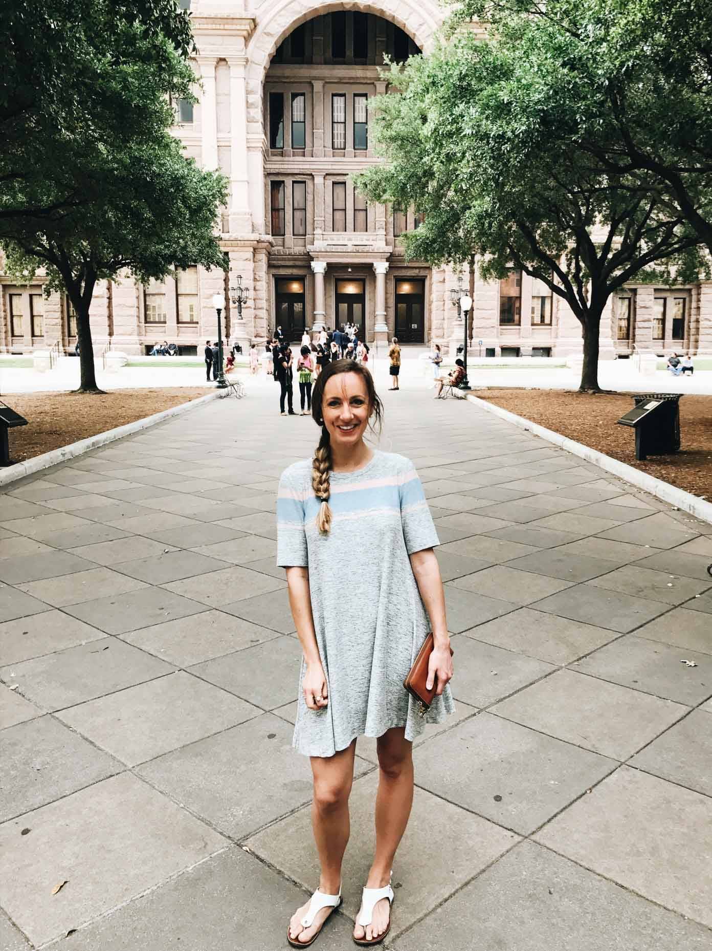 Woman wearing a dress standing on a sidewalk.