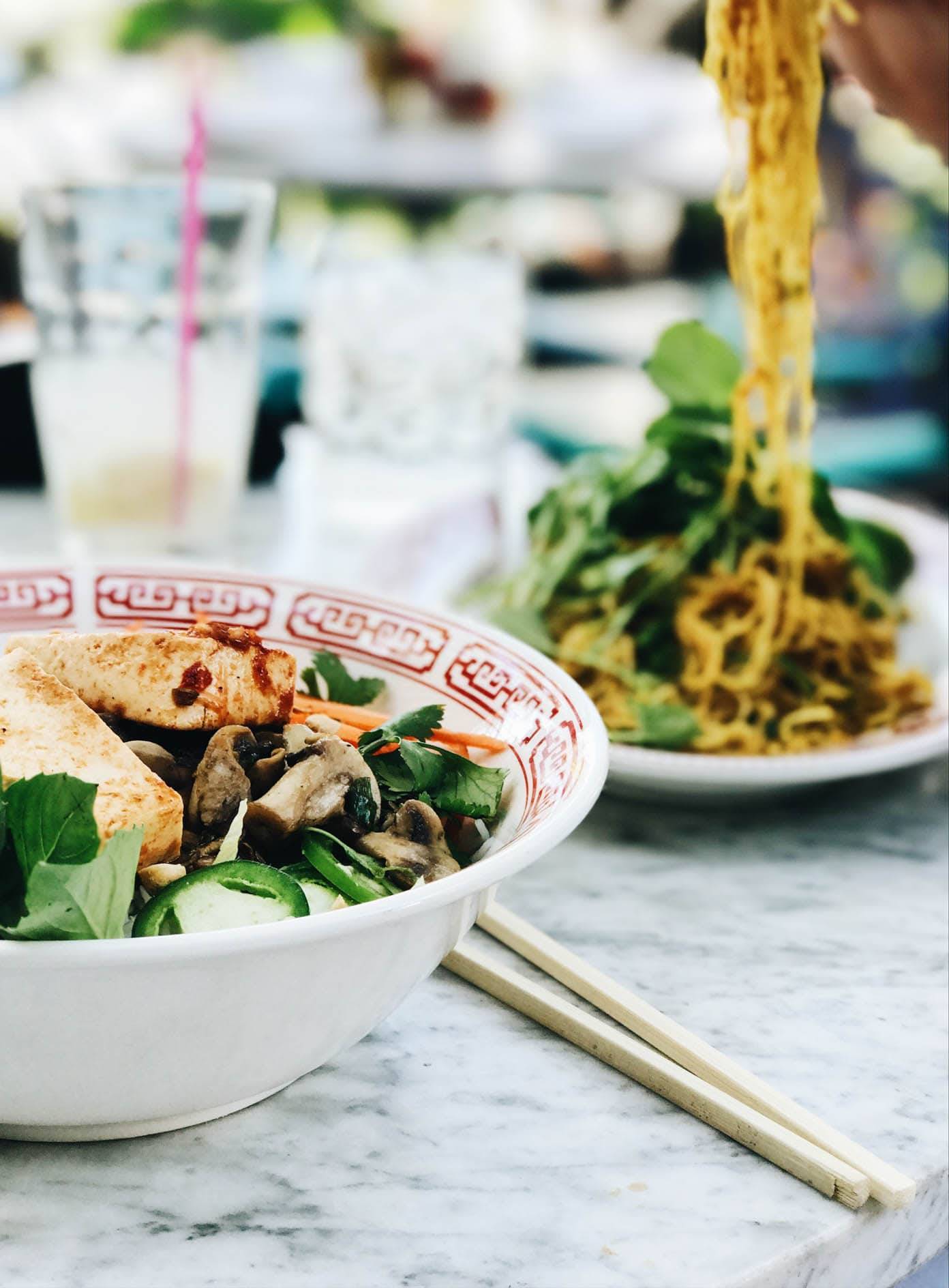 Food in a bowl and on a plate with chopsticks.