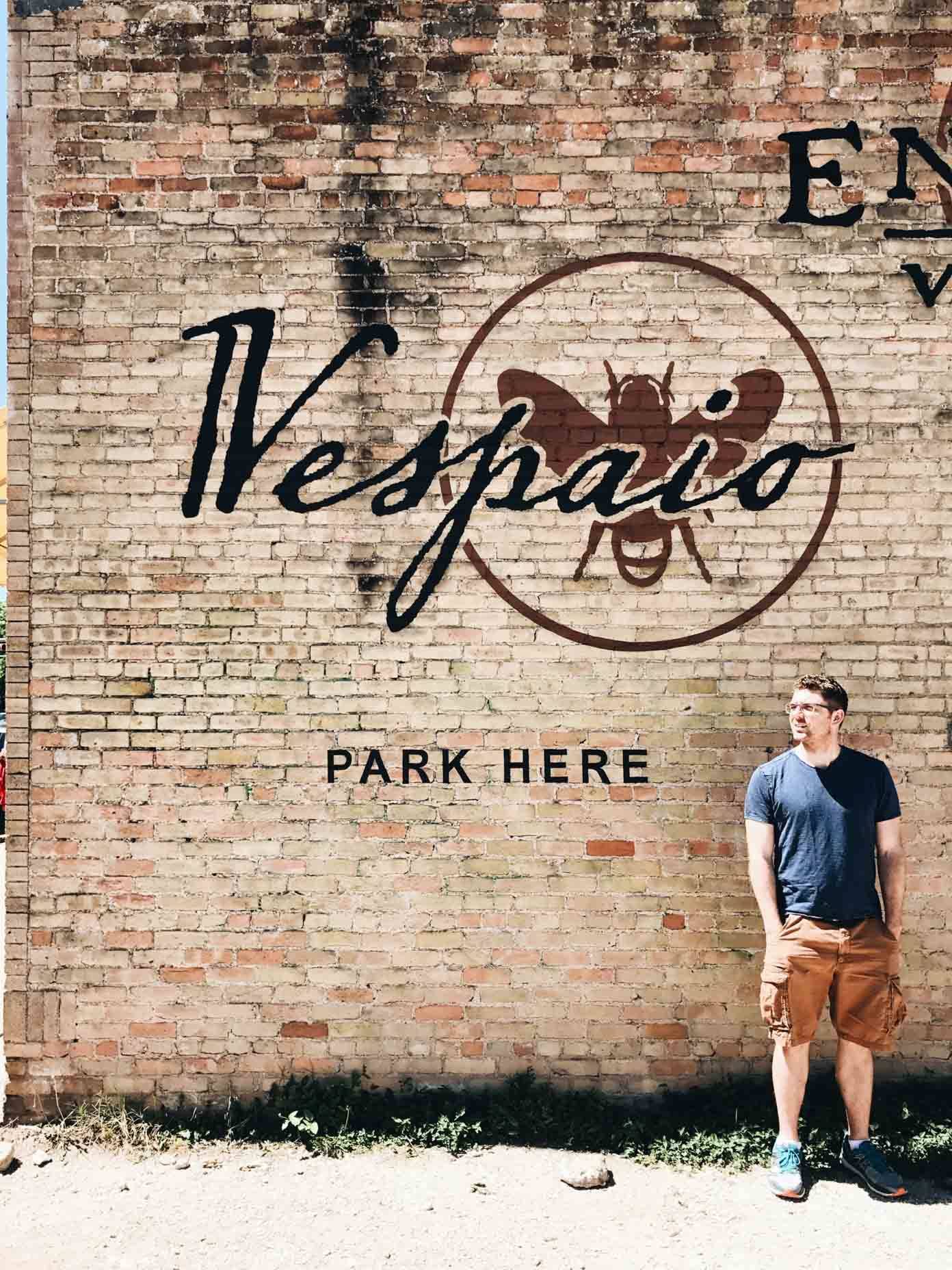 Man standing near a brick wall.