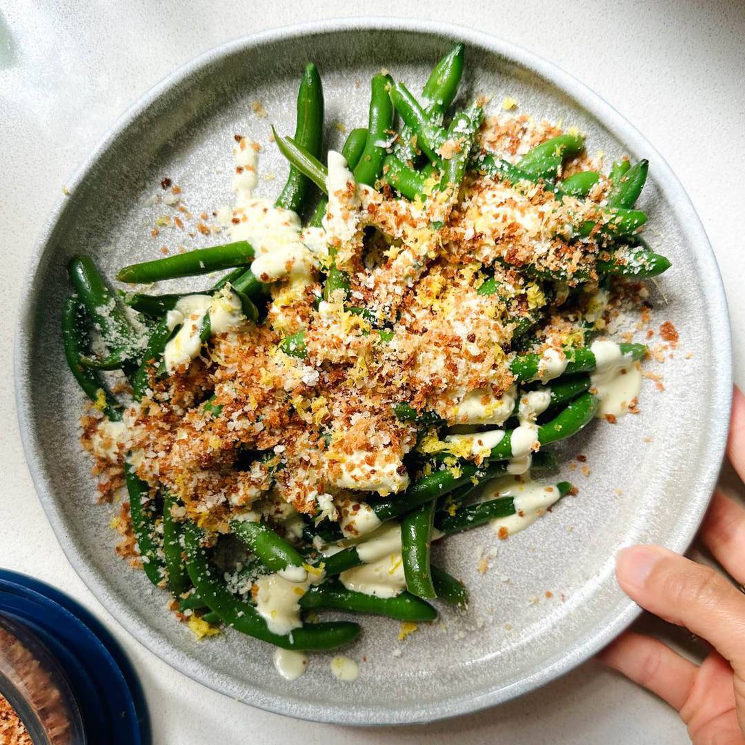 Avocado caesar green beans on a plate with panko on top.