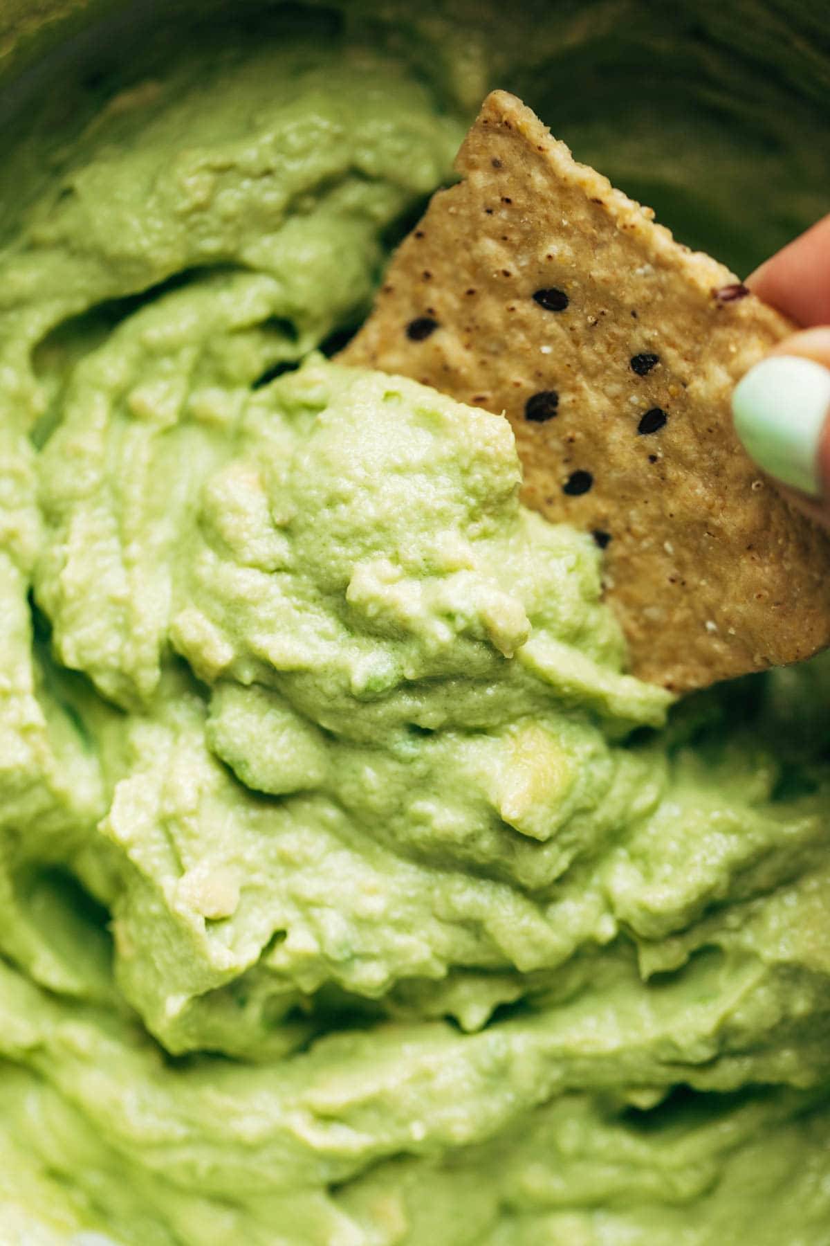 Closeup of chip dipped into Creamy Avocado Dip.