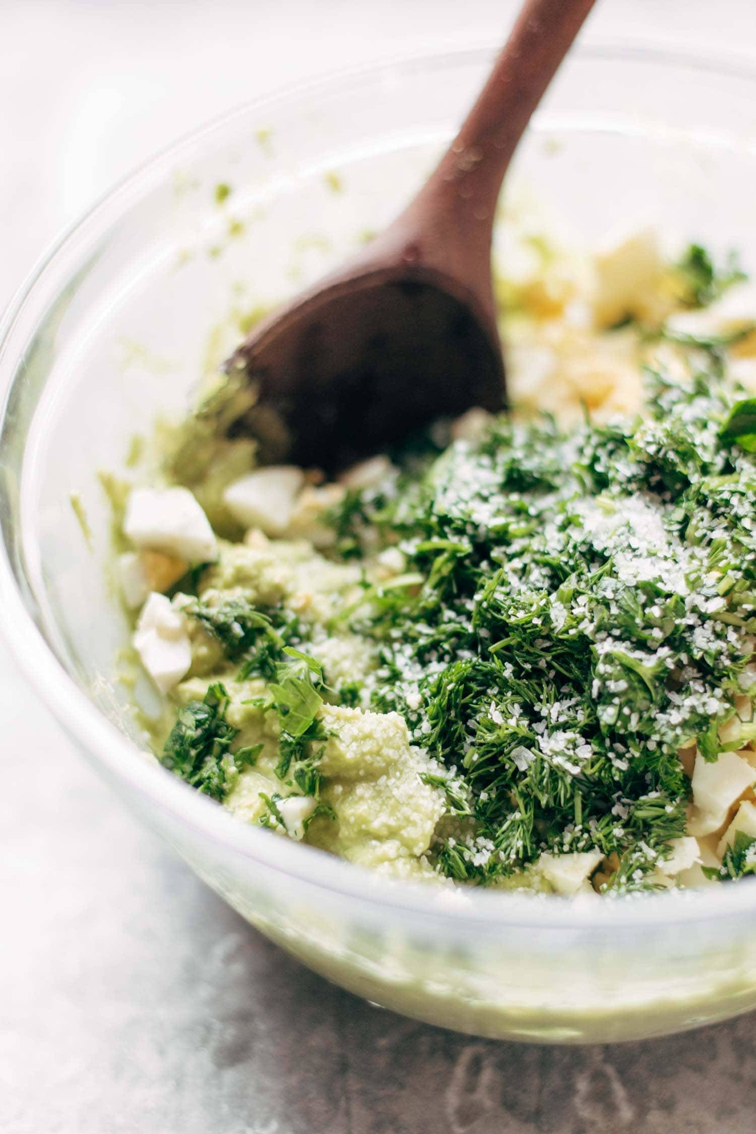 Avocado Egg Salad in a bowl with a wooden spoon.