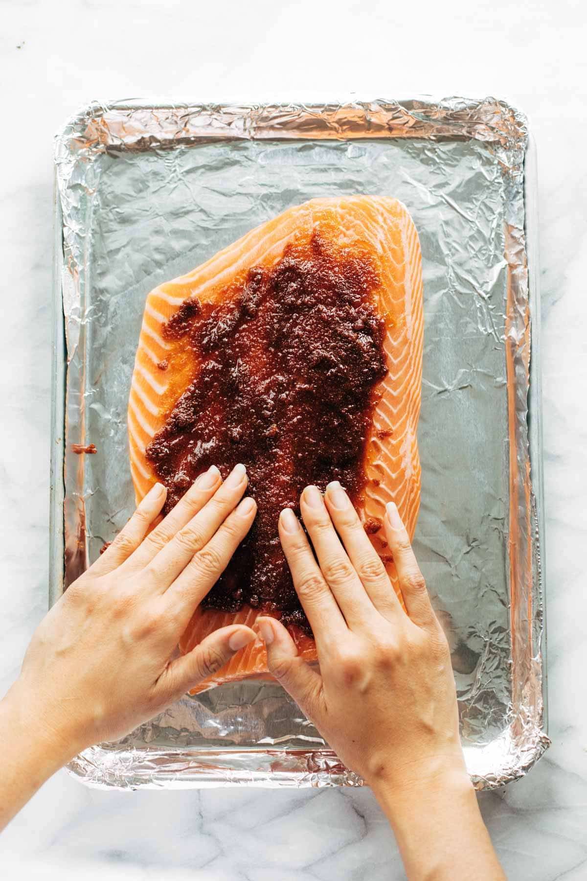 Adding rub to salmon on sheet pan.