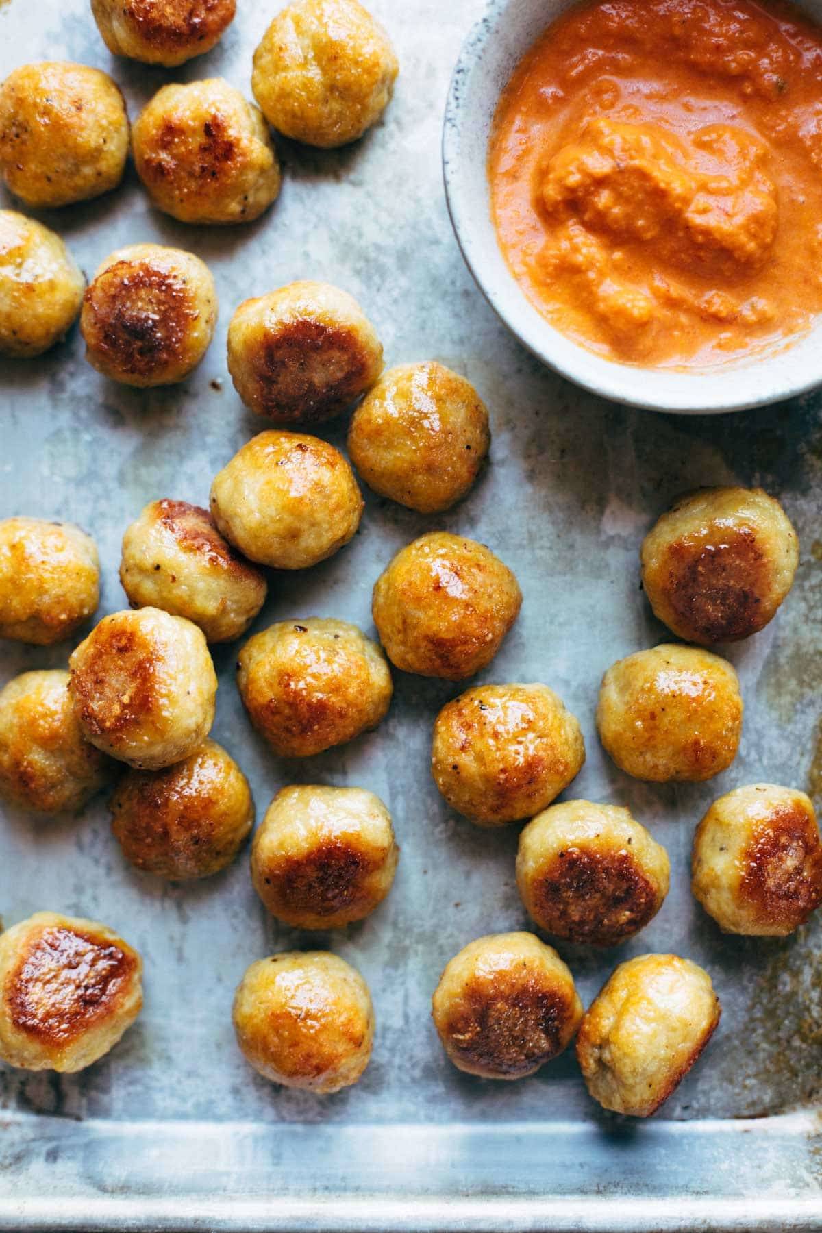 Baked Chicken Meatballs on a sheet pan with romesco sauce.