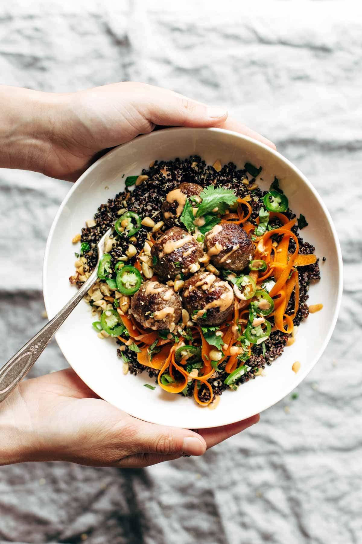 Hands holding a banh mi bowl with a fork.