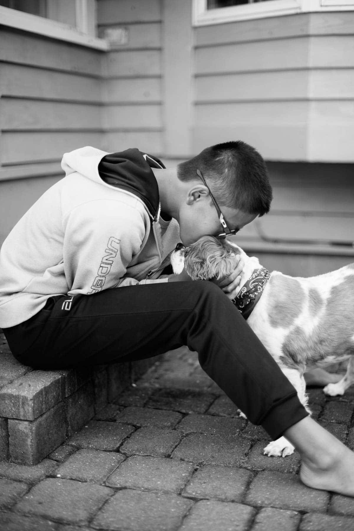 Boy kissing a dog.