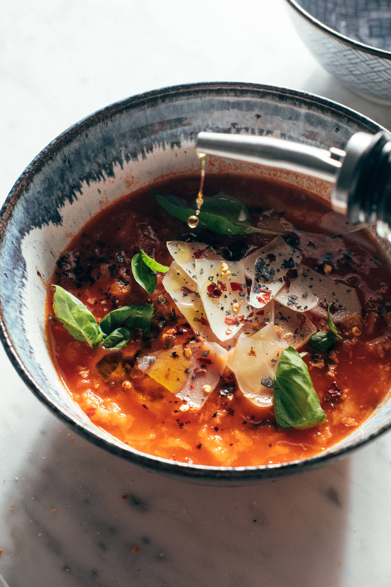 Olive oil being poured into tomato and bread soup