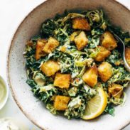 A brussels sprouts salad with croutons and a lemon.