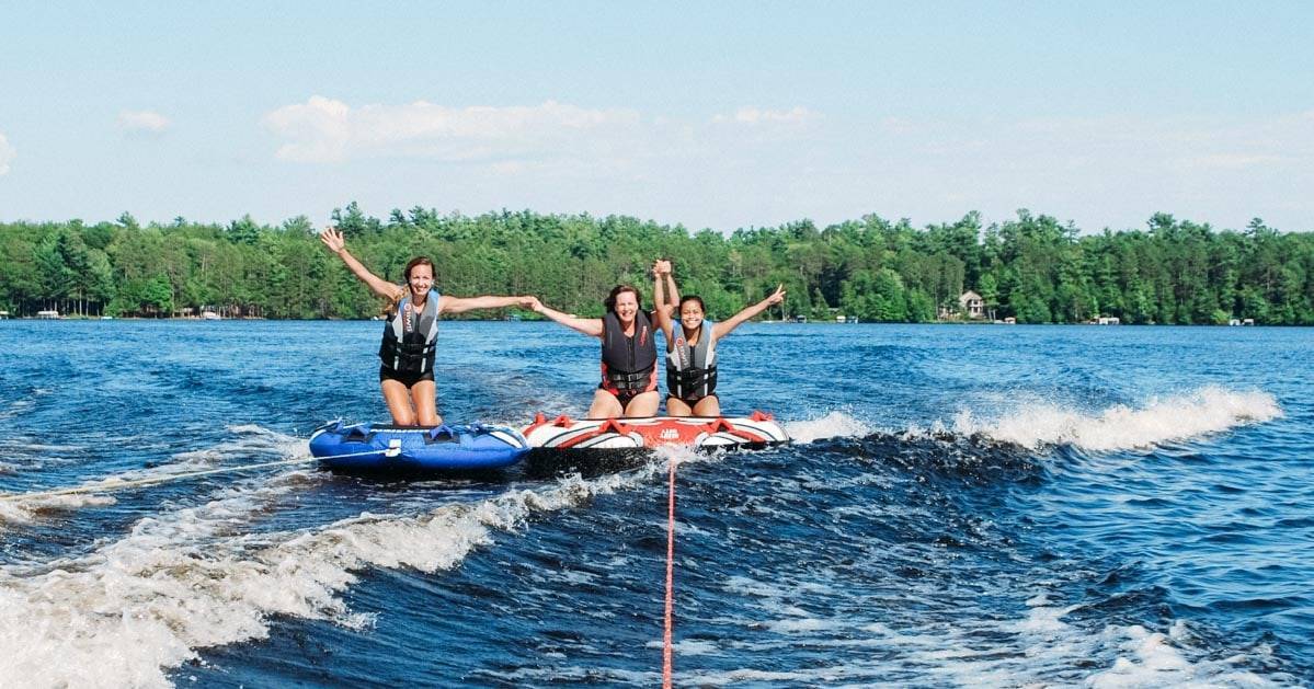 Three girls tubing on a lake.