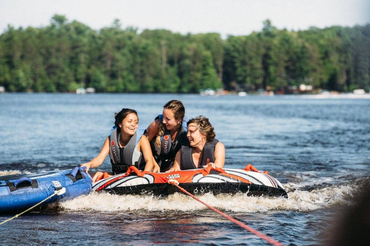 Three women tubing on a lake.