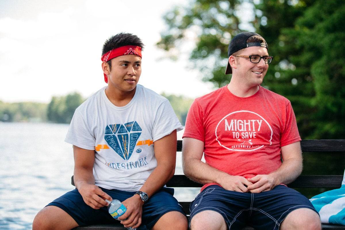 Two men sitting on a dock on the lake.