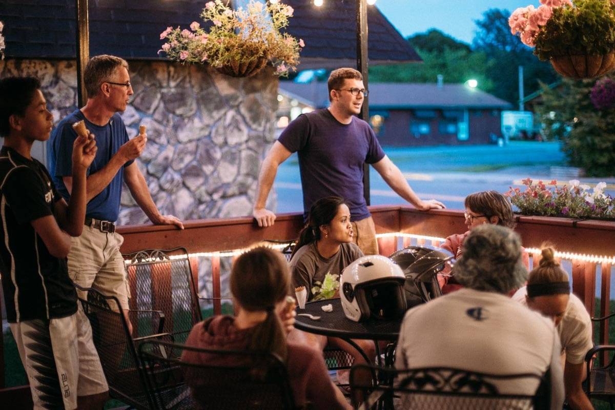 People eating ice cream around a table outside.