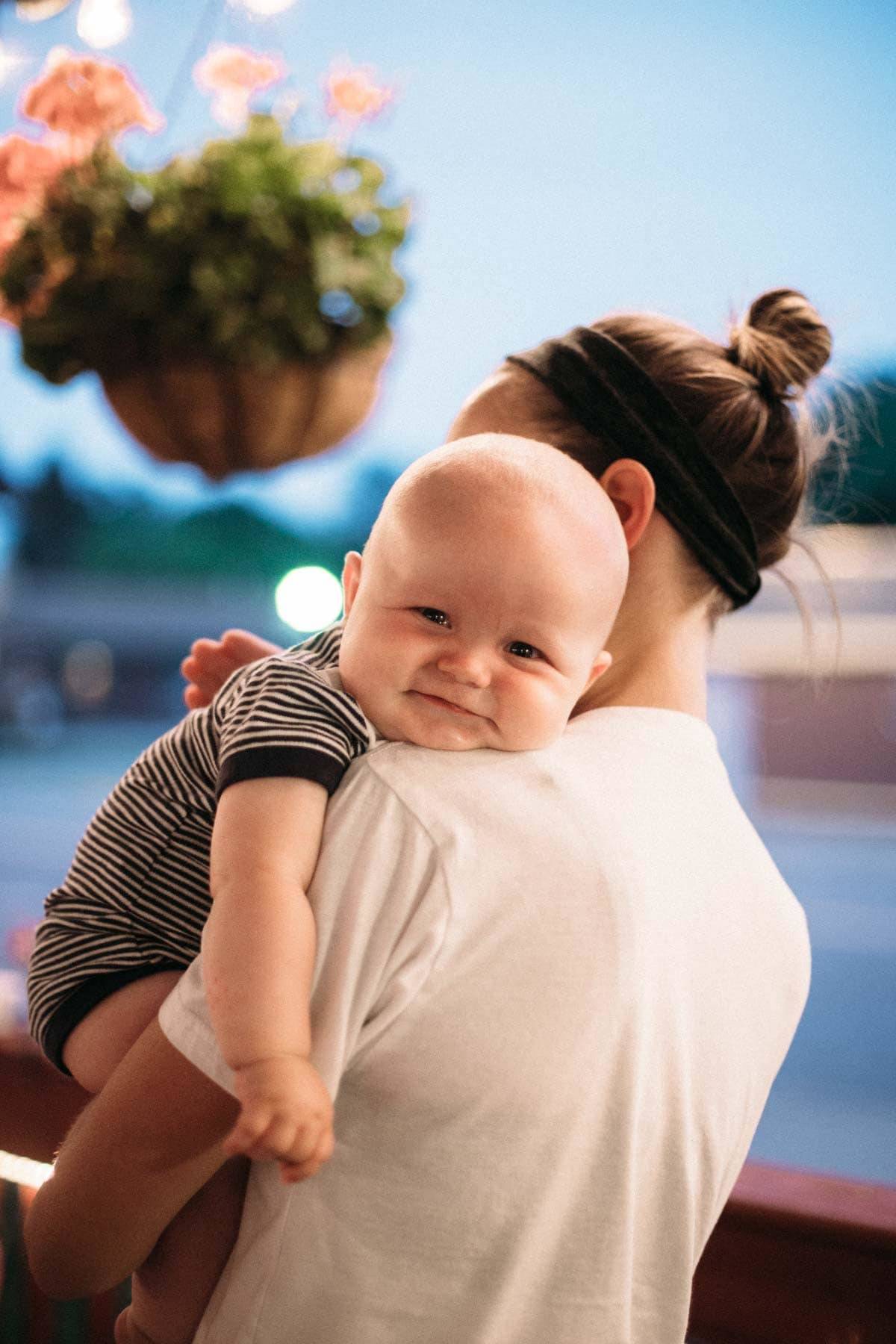 Woman holding a baby on her shoulder.