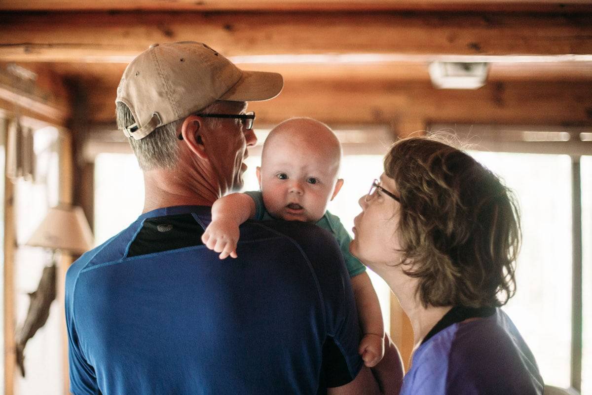 Man and woman reaching to kiss a baby boy.