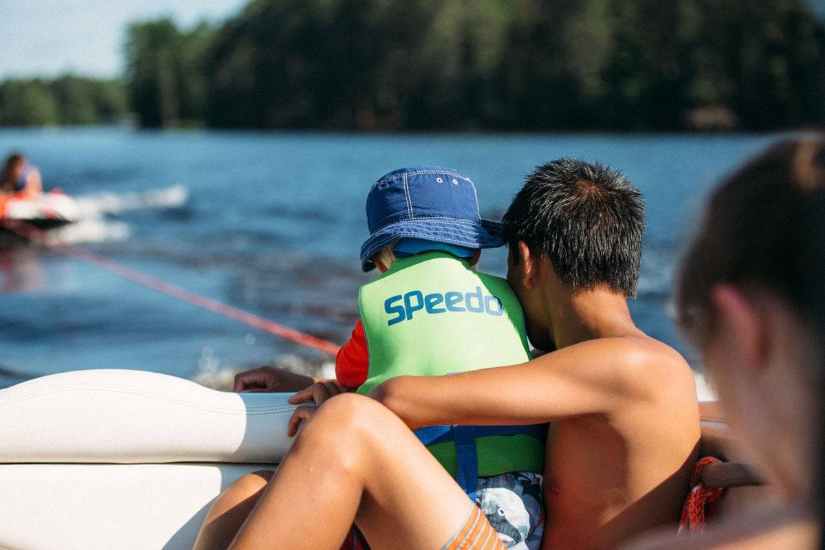 Two boys looking out the back of a boat.