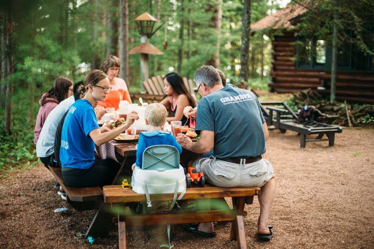 People sitting around a table at a cabin eating.