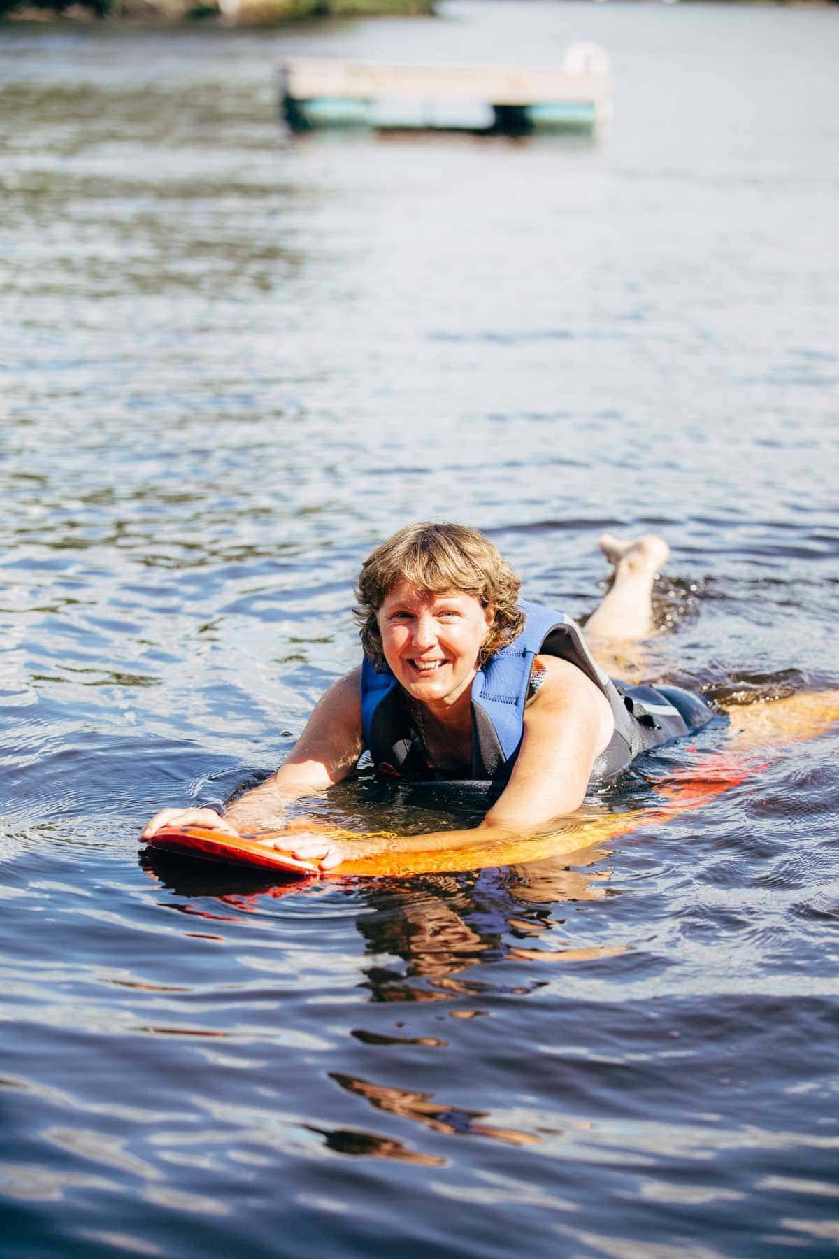 Woman laying on a board in the water.