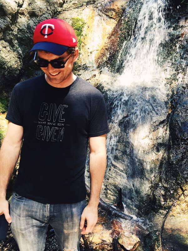 Man standing next to a waterfall.