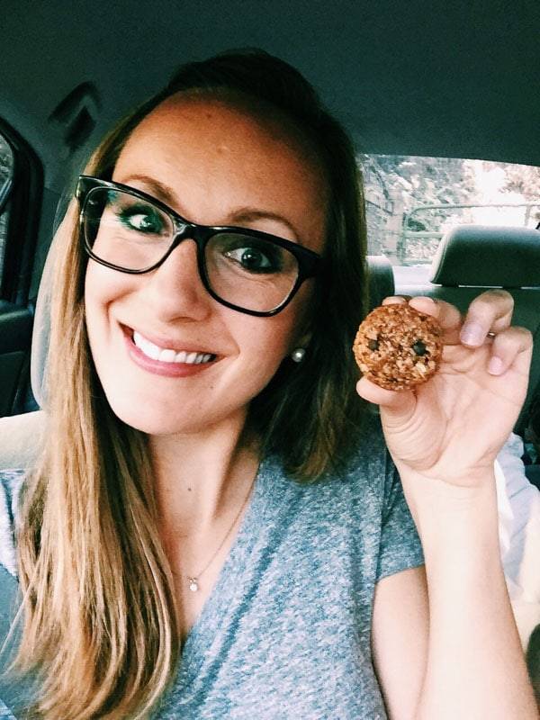 Woman wearing glasses holding a snack.