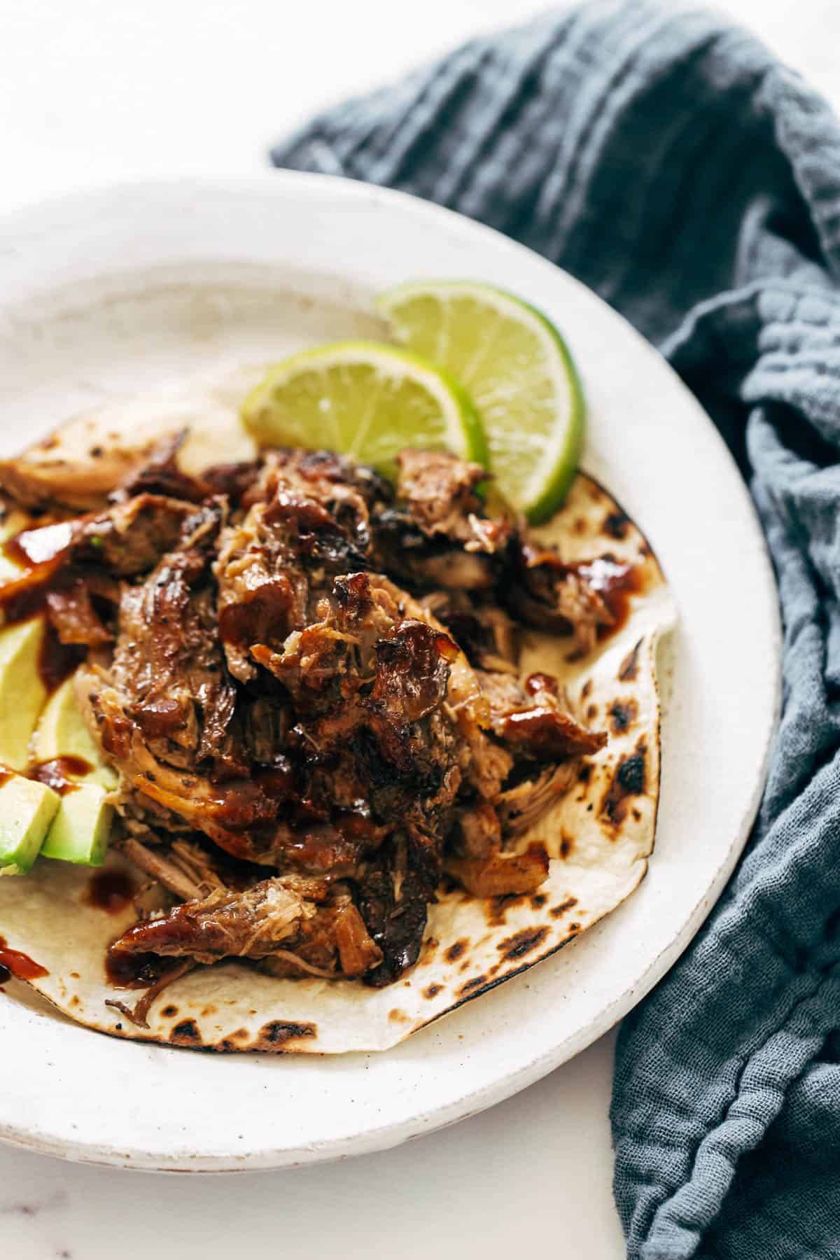 Carnitas in a tortilla on a plate with limes