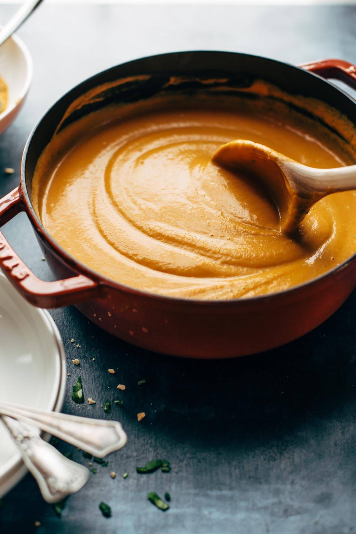 Spicy Vegan Carrot Soup in a pan with a wooden spoon