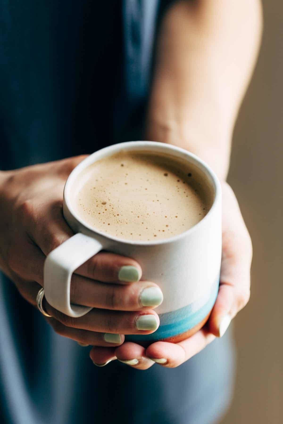 Hands holding a mug of Cashew Coffee.