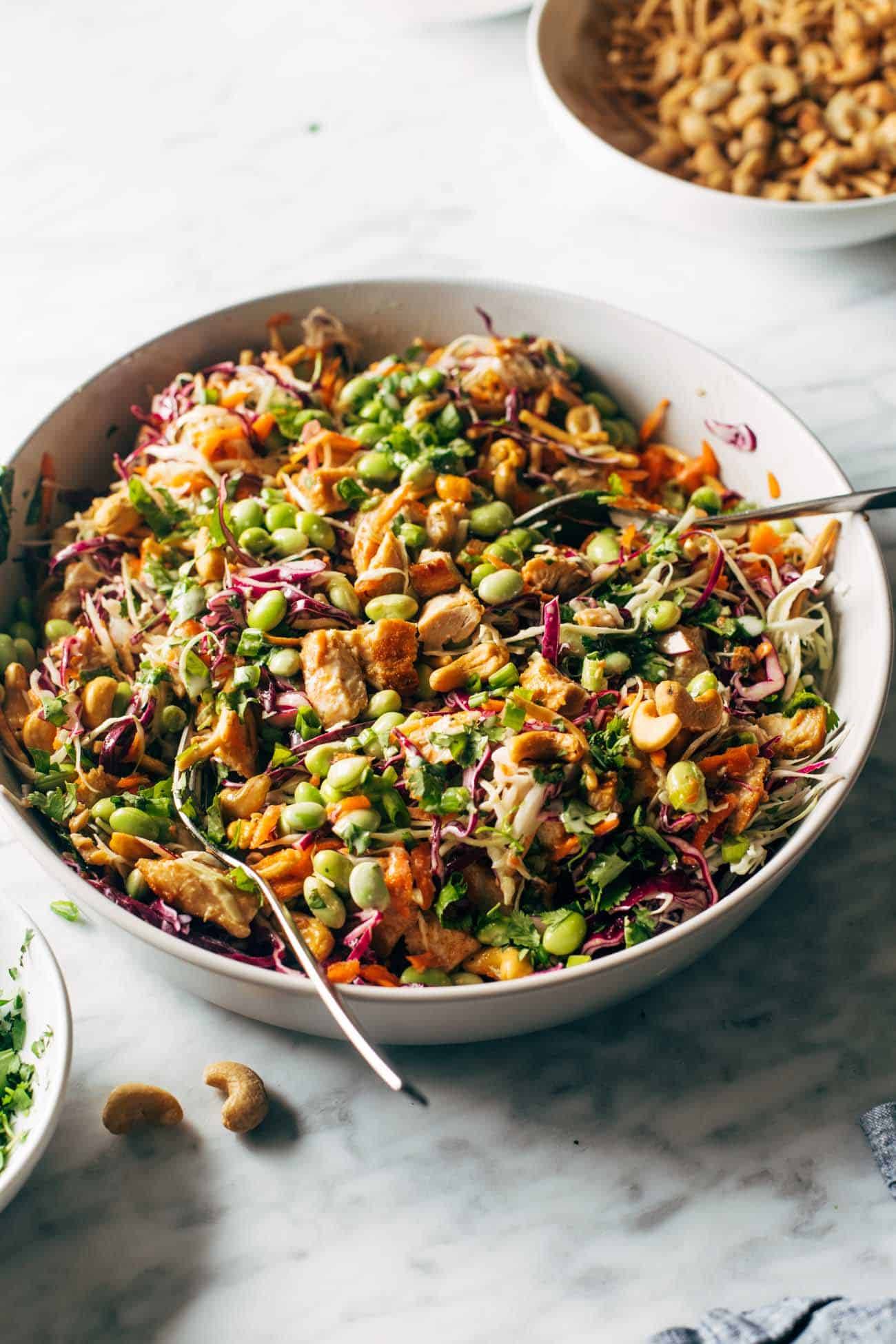 Cashew crunch salad in a bowl with a spoon and a bowl of cashews in the background. 