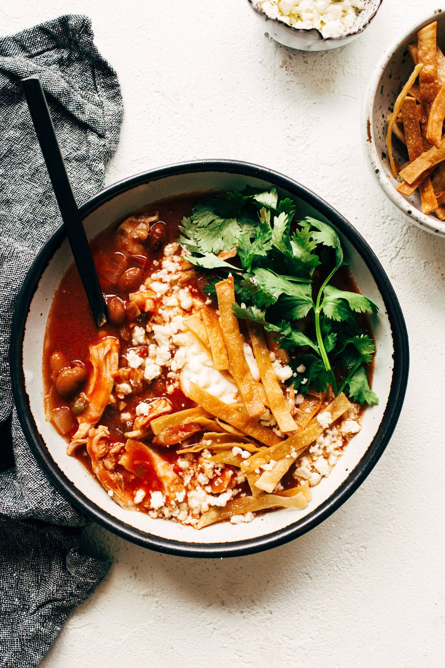 Chicken Tortilla Soup in a bowl with toppings and a spoon.