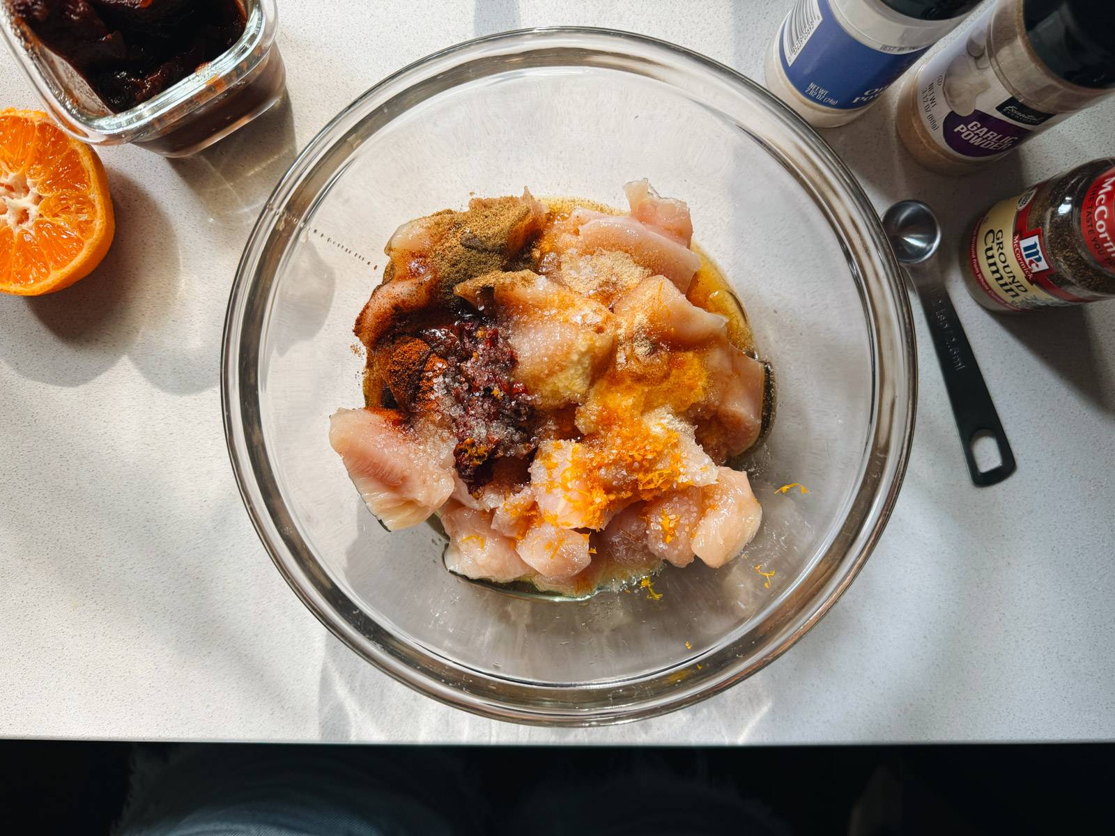 Mixing cubed chicken in a bowl with spices.