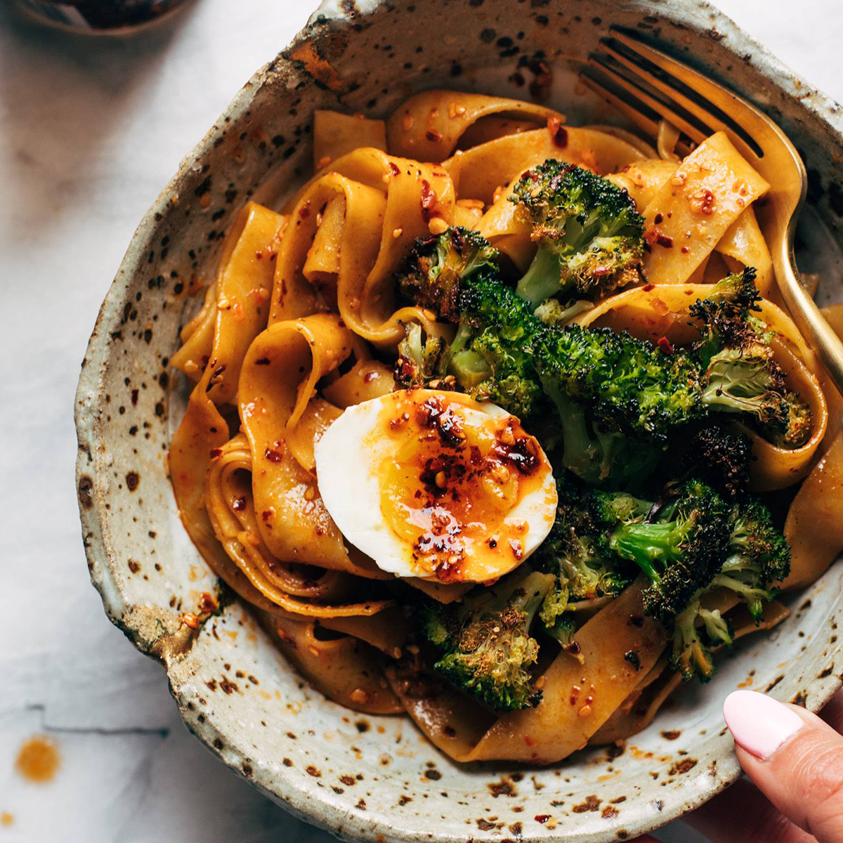 Pappardelle in a bowl with broccoli, egg, and chili crisp.