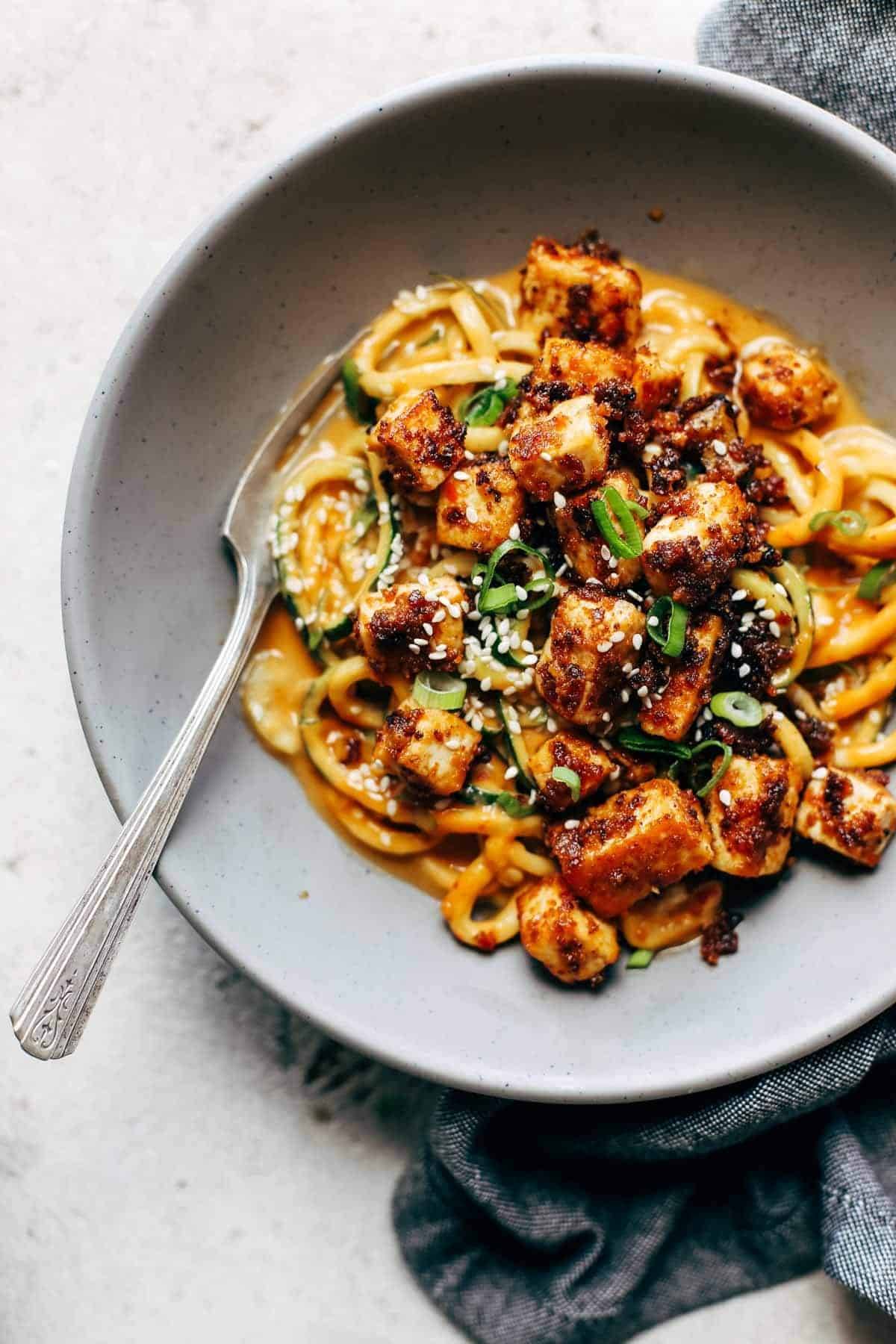 Zoodles with tofu on a plate with a fork.