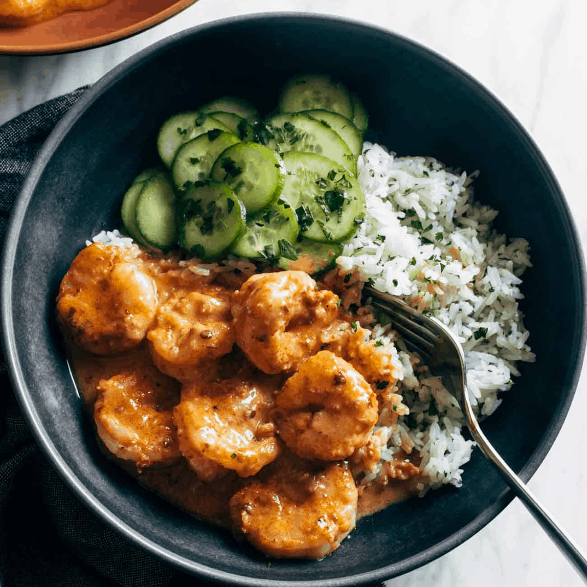 Creamy chipotle shrimp in a bowl with rice and cucumbers.